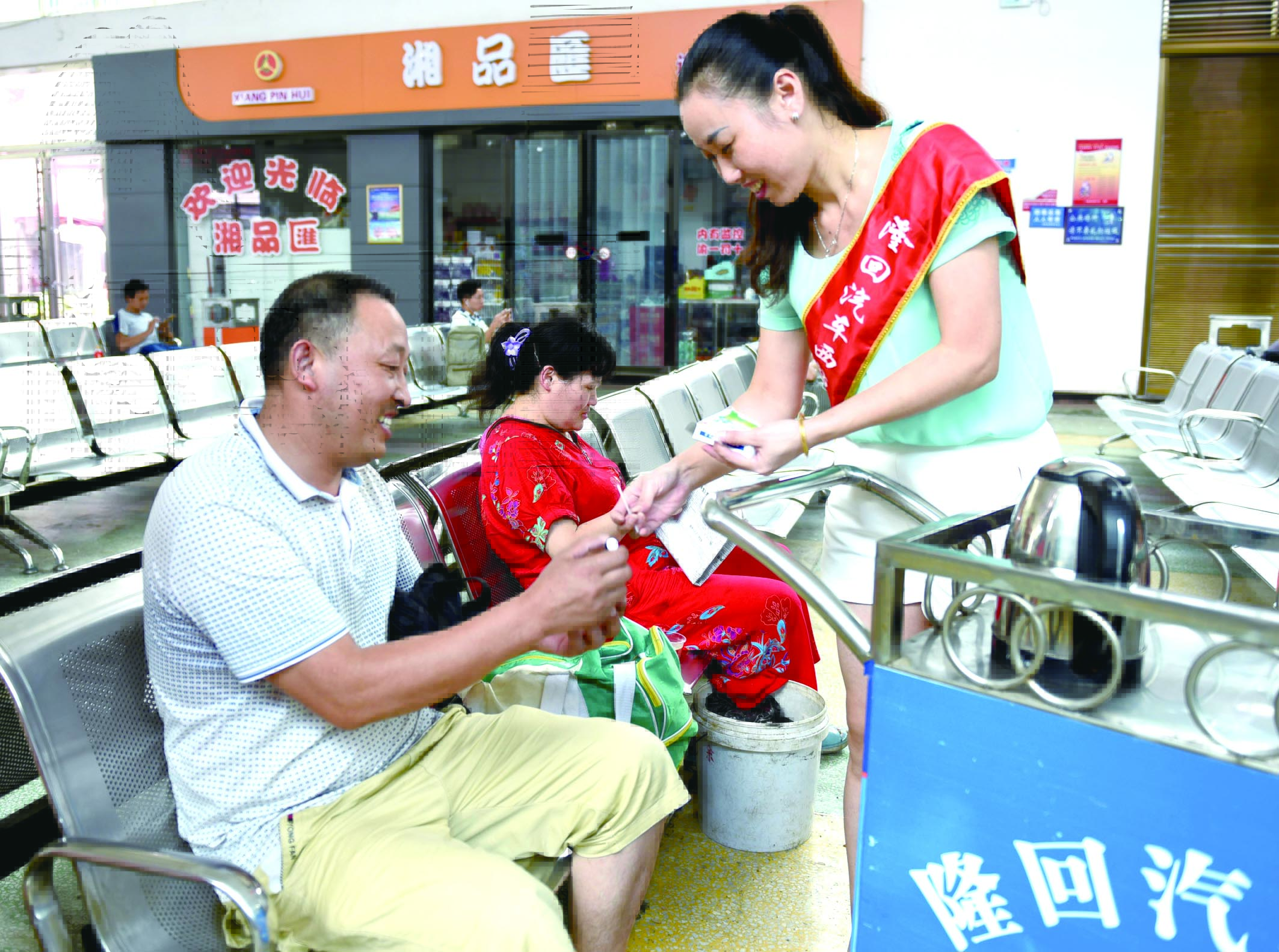 隆回分公司汽車西站工作人員正在為旅客免費贈送藿香正氣水。